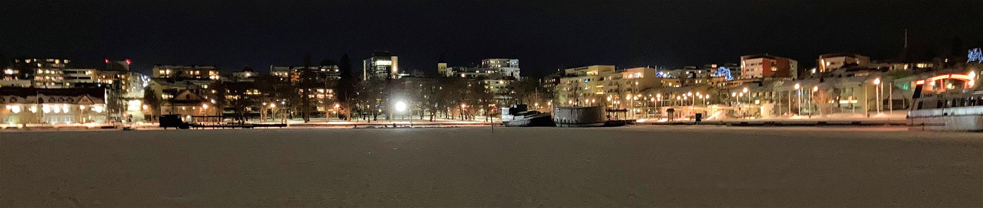 Kaupungin siluetti Kaupunginlahden jäältä päin iltavalaistuksessa